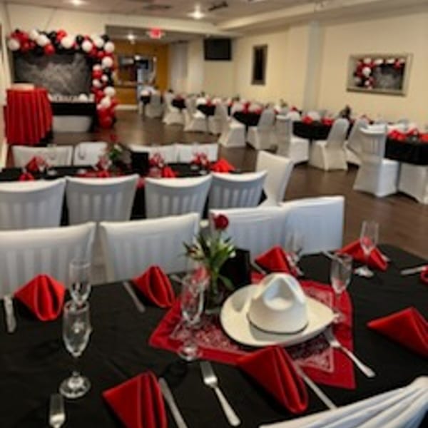 A decorated dining room at Tequila's 55 with tables set in red and black, and balloon arches.