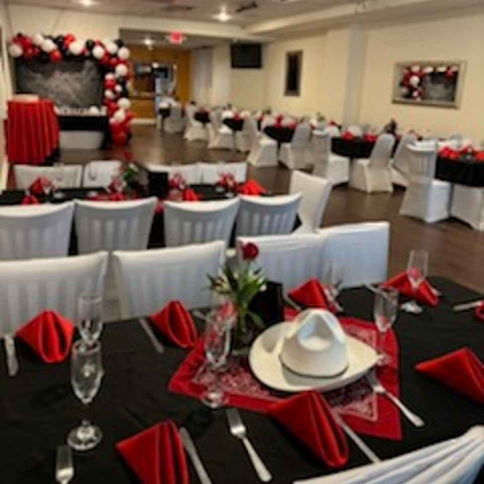 A decorated dining room at Tequila's 55 with tables set in red and black, and balloon arches.
