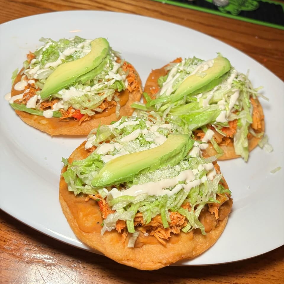 Three Tequila's 55 sopes with shredded chicken, lettuce, sour cream, and avocado slices.
