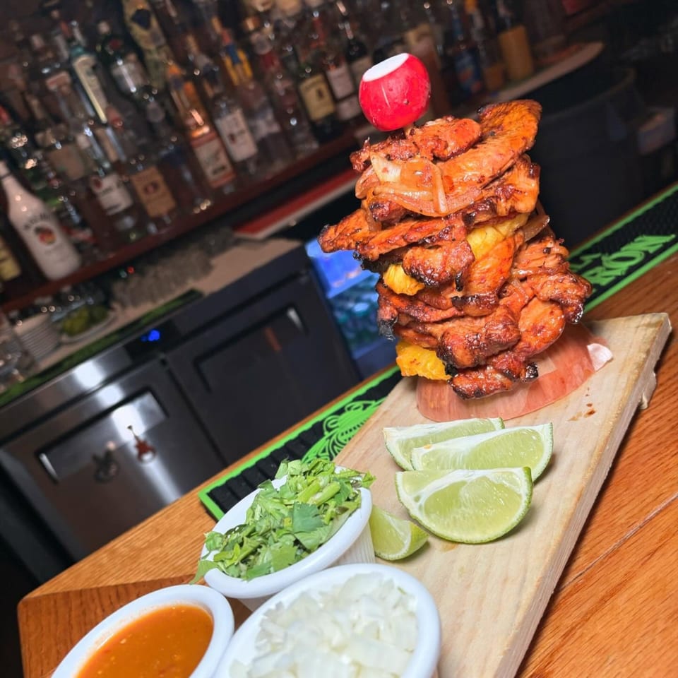 Tequila's 55 al pastor meat tower with pineapple, radish, limes, cilantro, onions, and salsa.